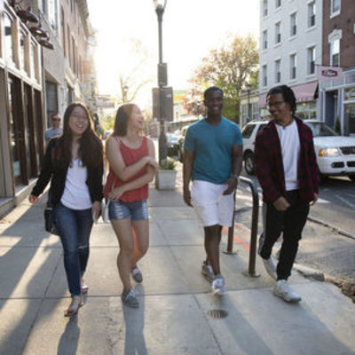 Four students walking down a street in the city